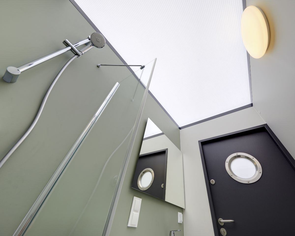 Binnenkant van badkamer met douche en deur met rond raam.