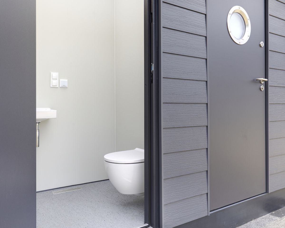 Deur van cabana met rond raam en uitzicht op toilet.
