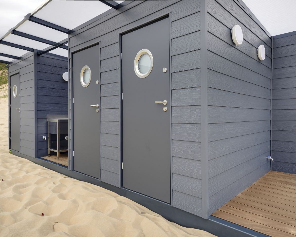 Verschillende grijze cabana's met ronde ramen op het strand.