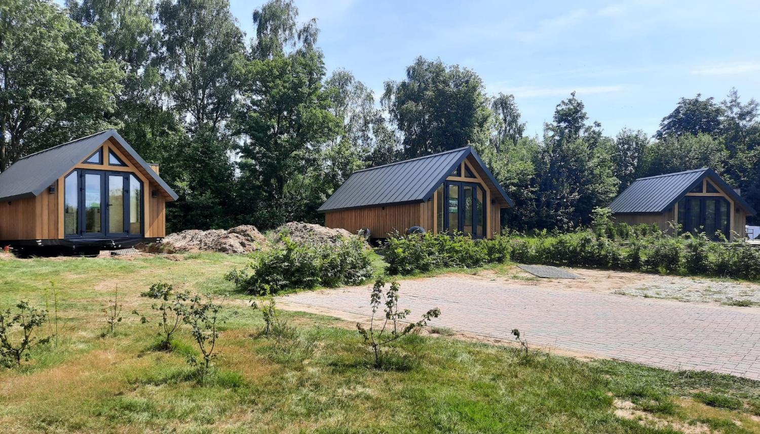 Rij van drie kleine, houten vakantiehuizen met een pad.