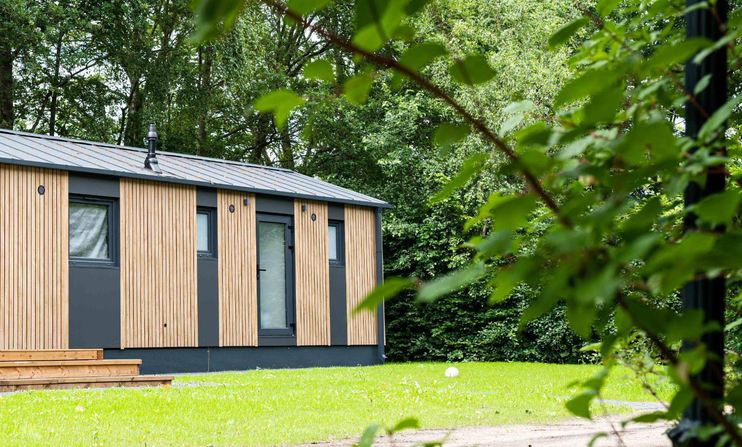 Zijkant van een moderne vakantiewoning met houten en grijze gevel.