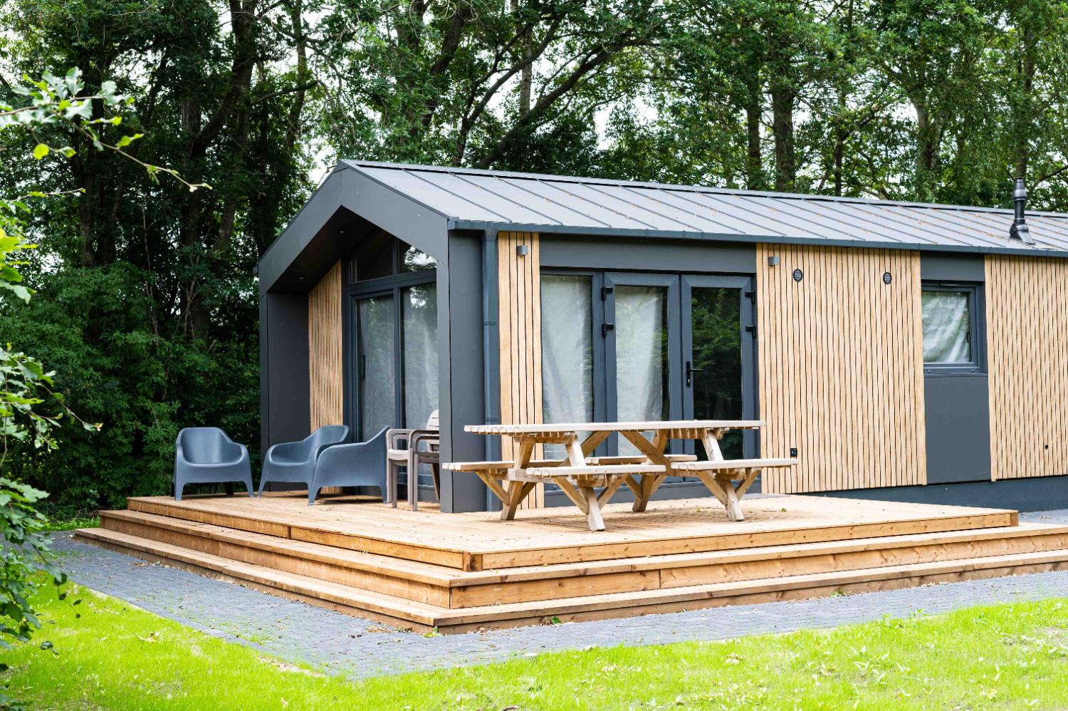 Moderne vakantiewoning met een houten terras en een picknicktafel.