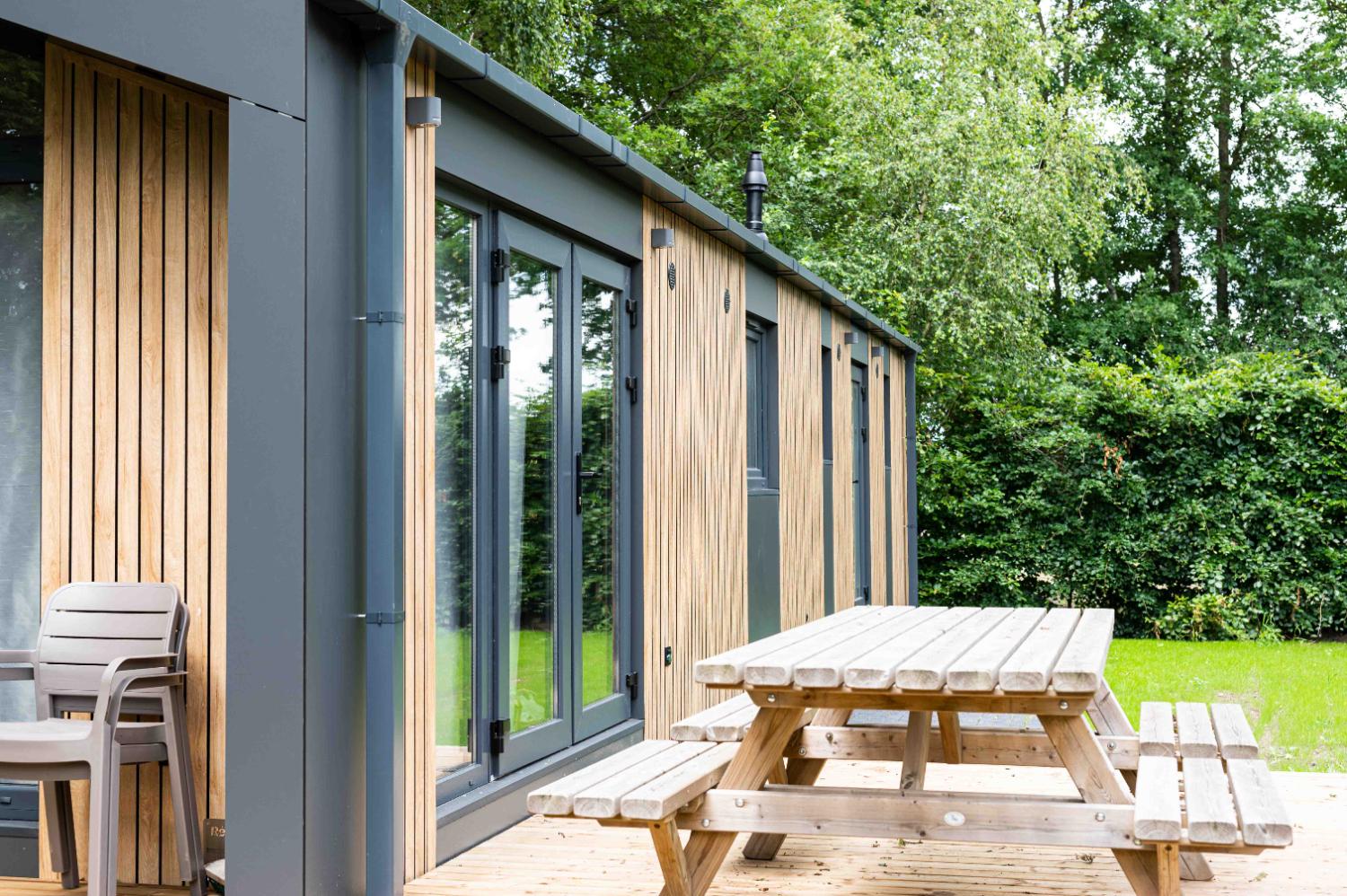 Lange, moderne vakantiewoning met houten terras en picknicktafel.