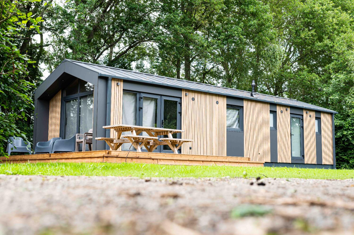 Lange, moderne vakantiewoning met houten terras en picknicktafel.