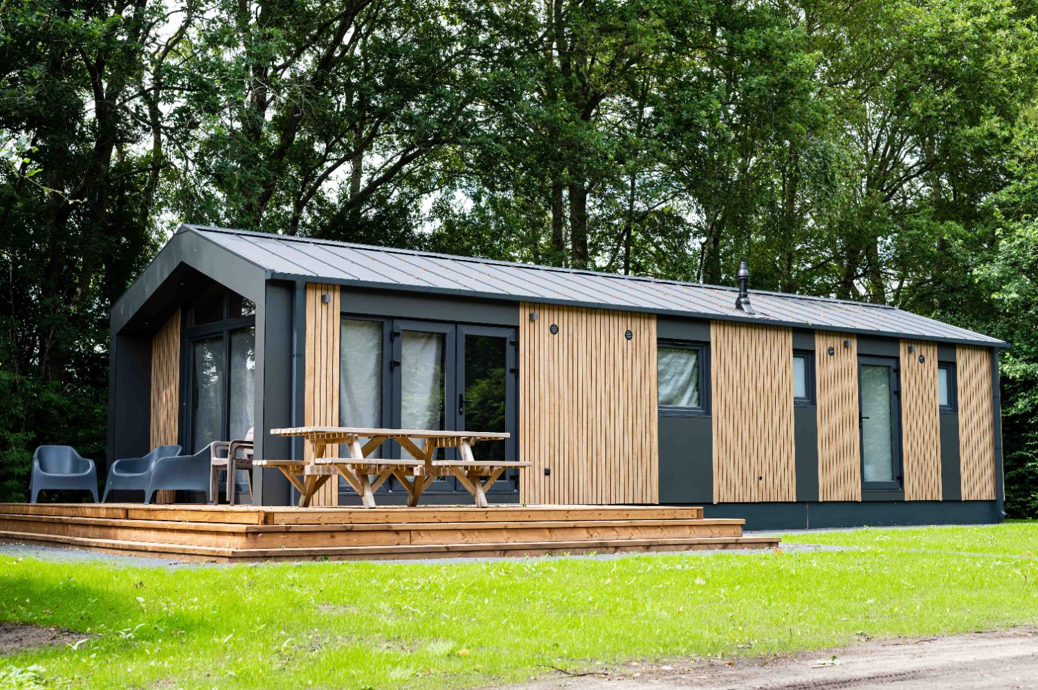 Lange vakantiewoning met een houten terras en een picknicktafel.