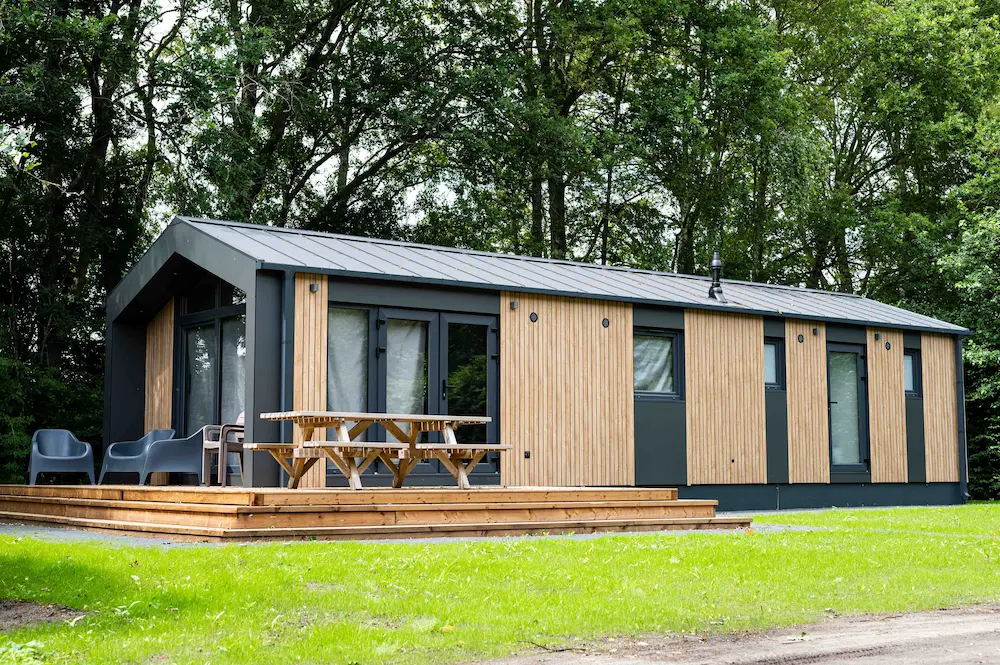 Moderne vakantiewoning met een houten terras en een picknicktafel.