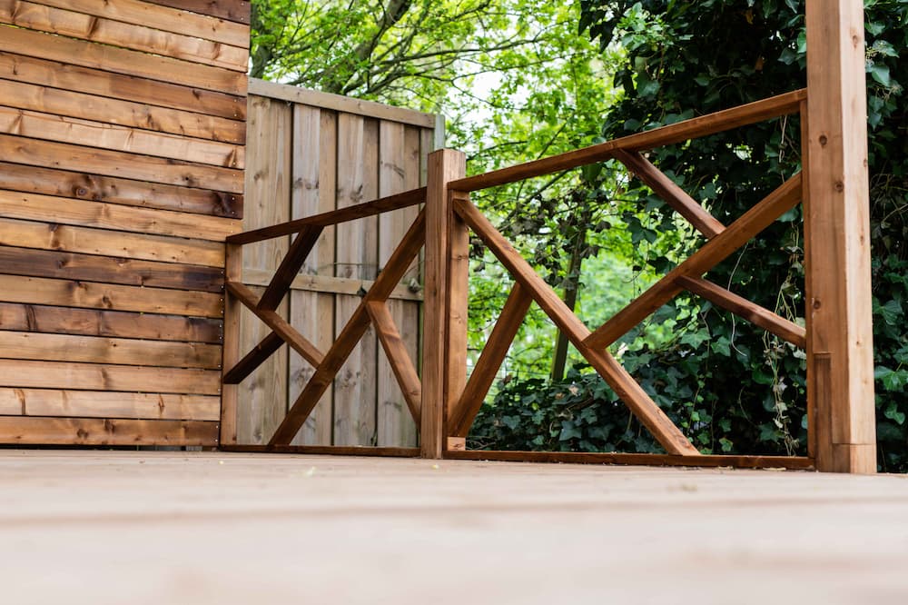 Close-up van een houten balustrade met geometrisch patroon op een terras.
