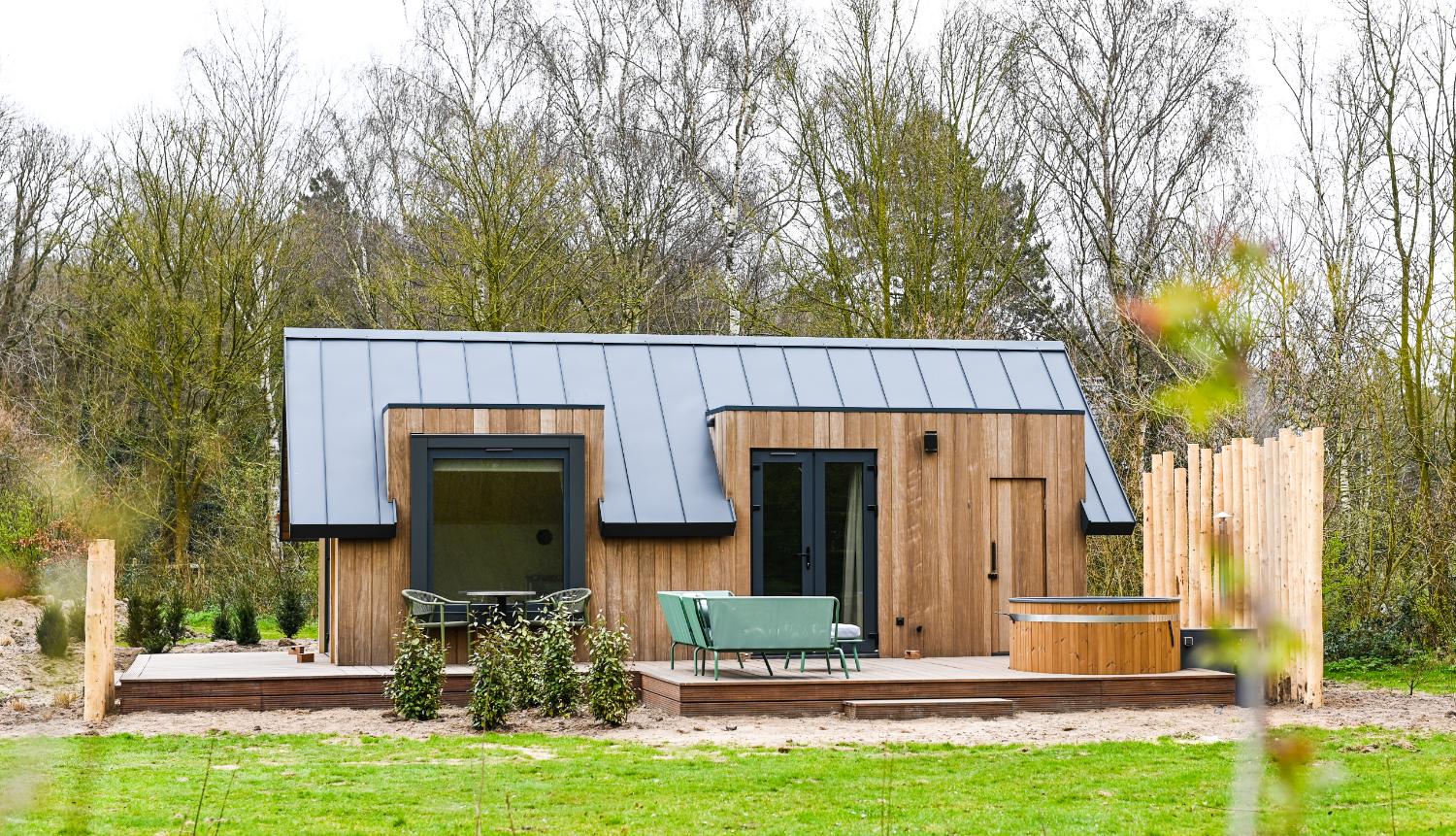 Lange, houten vakantiewoning met een hottub en grijs dak.