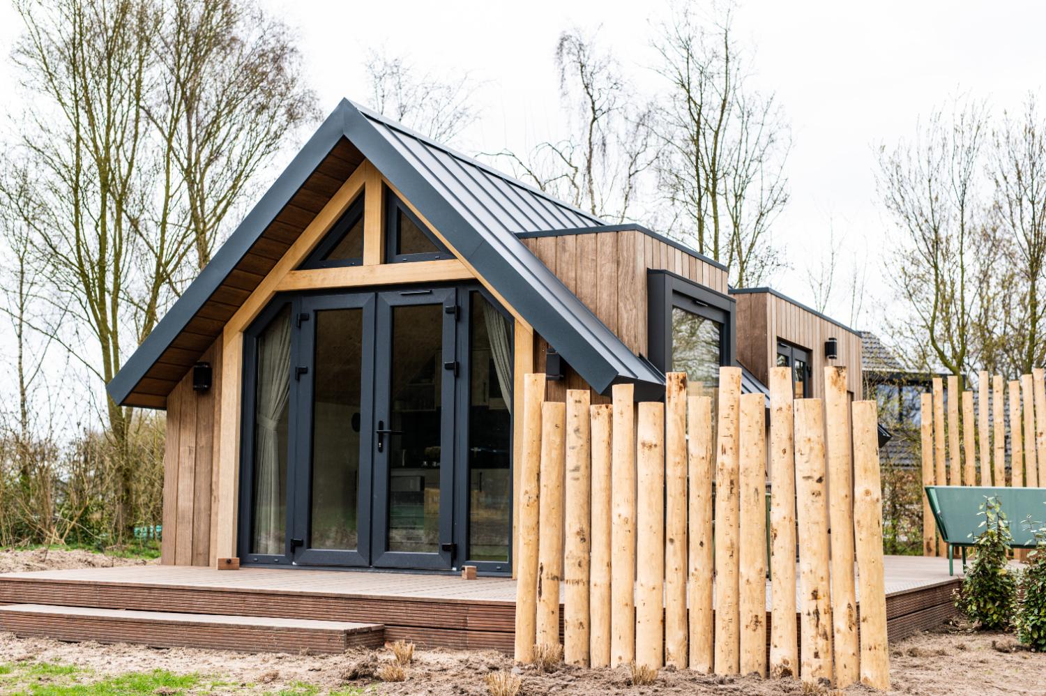 Modern houten vakantiehuis met puntdak, terras en houten schutting.